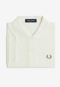 Crème-kleurige polo-shirt van textuurstof, met een kraag, een drie-knopen sluiting en een klein geborduurd logo op de borst.