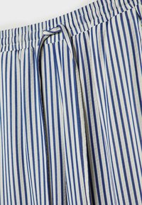 Blauw-wit verticaal gestreepte stof met een elastische tailleband en een gestrikt koord in het midden voor.