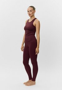 Bordový športový tank top a legíny. Hladká látka, priliehavý strih, bezrukávový top s okrúhlym výstrihom, bezšvový pás na legínach.