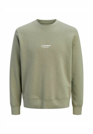 Puha anyagból készült zöld pulóver, kerek nyakkal, hosszú ujjakkal, valamint a mellkason egy kis fehér logóval a márkajelzéshez.