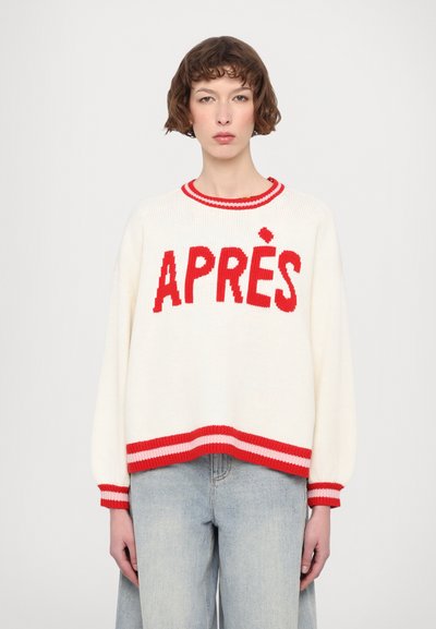 Hvid strikket sweater med "APRÈS" i røde blokbogstaver. Har røde og lyserøde striber ved kraven og kanten, samt puffede ærmer.