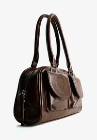 Dunkelbraune Lederhandtasche mit zwei Frontklappenfächern und doppelten runden Griffen, fotografiert auf einem weißen Hintergrund.