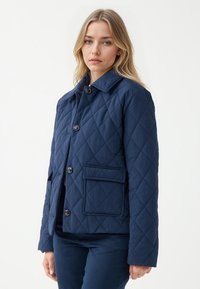 Giacca trapuntata navy con colletto, chiusura anteriore con bottoni e tasca singola. Presenta un tessuto testurizzato e una vestibilità su misura.