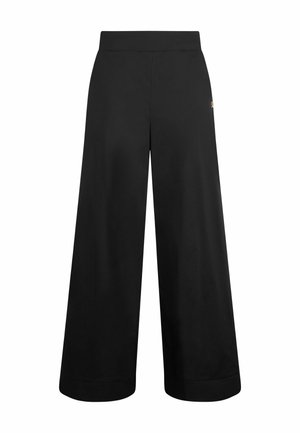 Des pantalons larges noirs présentent une texture lisse et mate, une taille élastique et un petit logo doré sur le côté.