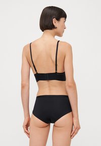 Black lingerie set featuring a simple design with adjustable straps, a hook closure, and smooth texture on both the bra and high-waisted panties.