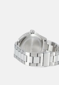 Silberner Metallarmbanduhr mit gebürsteter und polierter Oberfläche, ausgestattet mit einem runden Gehäuse, einem Gliederarmband und einer Krone an der Seite.