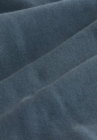 Sötétkék szövet közeli felvétele, amelyen puha textúra látható, finom kopási vonalakkal és egységes szövési mintával. Különböző textilalkalmazásokhoz alkalmas.