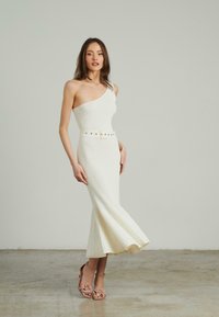 Weißes, schulterfreies, geripptes Midikleid mit ausgestelltem Saum, umgeben von einem Gürtel mit einer Schnalle und goldenen Nieten. Seidige Textur.