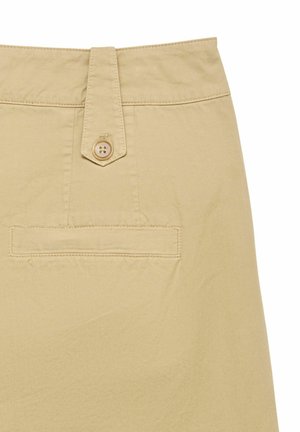 Dos d'un pantalon beige avec un seul rabat à bouton au-dessus d'une poche passepoilée horizontale sur fond uni.