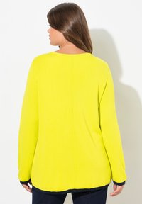 Maglione giallo brillante con maniche lunghe, texture a coste e orlo curvo. Presenta dettagli in blu navy scuro sui polsini e sull'orlo.