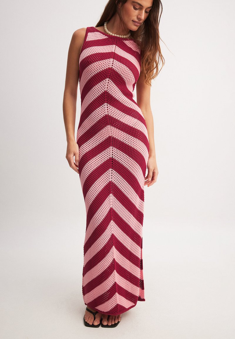 Kootud maksikleit punaste ja roosa chevroniribadega, ilma varrukateta disain ja sobiv vorm. Omab tekstureeritud kangast ja avatud kudet.