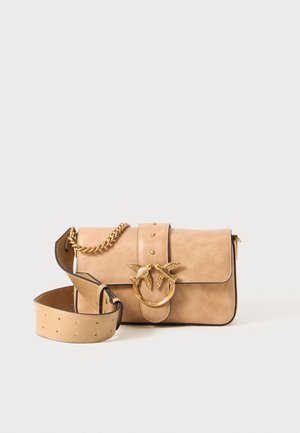 Beige leren handtas met een gestructureerde afwerking, gouden hardware in de vorm van een vogel, ketting en verstelbare schouderband, met een knoopsluiting en decoratieve studs.