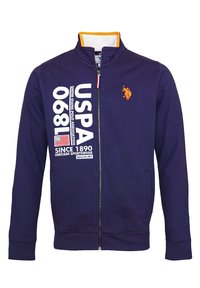 Mörkblå zip-up jacka med orange kragepålägg, USPA-logotyp, stor vit text "USPA 1890" och en liten orange polo-spelare emblem.