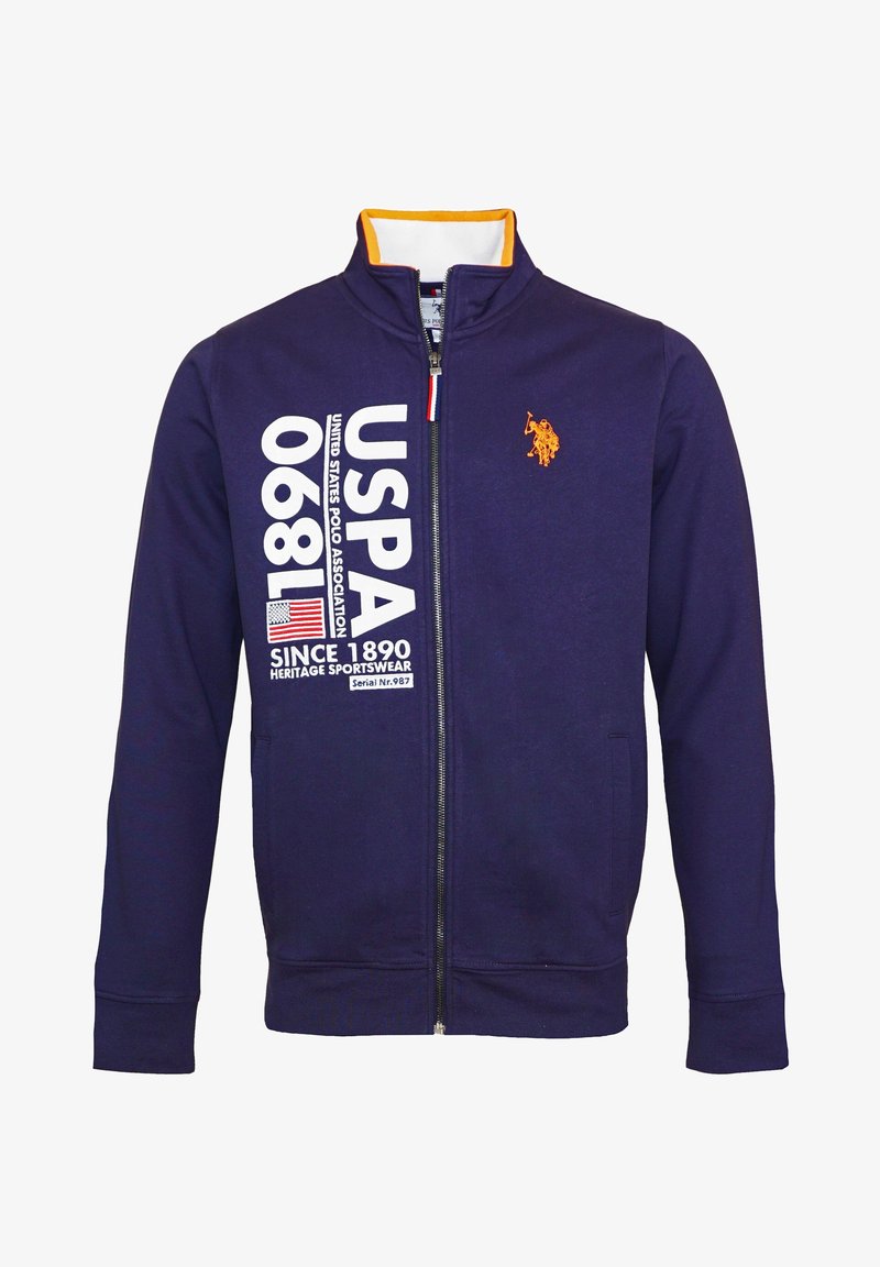 Mörkblå zip-up jacka med orange kragepålägg, USPA-logotyp, stor vit text "USPA 1890" och en liten orange polo-spelare emblem.