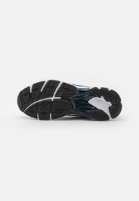 Running shoe sole featuring black rubber with textured grip, white accents along the sides, and a smooth blue and black molded upper.