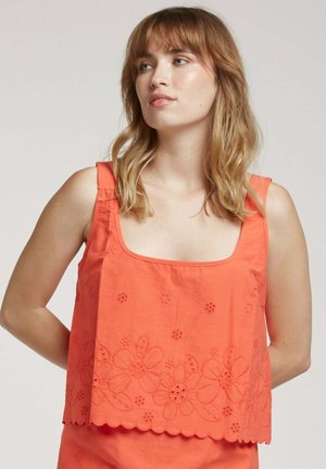 Haut croppé brodé orange avec décolleté carré, larges bretelles, motifs floraux le long de l'ourlet et bordures festonnées. Matériau en coton.