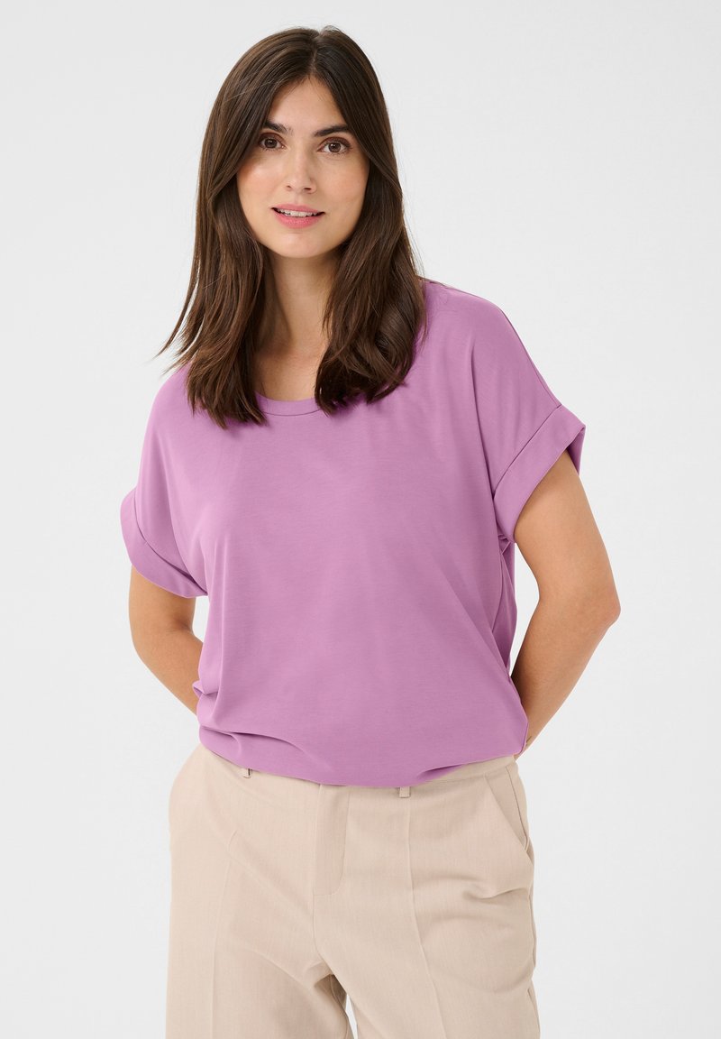 Viegls purpura īsās piedurkņu tops ar apaļu kakla izgriezumu un pavilktām piedurknēm, saskaņots ar bēžām biksēm. Gluda tekstūra, ikdienišķa piegriezuma.