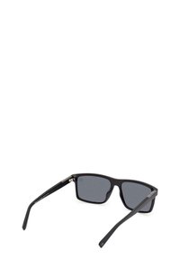 Gafas de sol rectangulares negras con lentes grises, con un acabado mate, varillas delgadas y sutiles acentos metálicos en las bisagras.