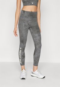 Gray fitness leggings with a textured pattern, high waistband, and white "PROJECT ROCK" lettering on the left leg. Paired with white sneakers.