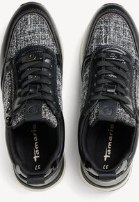 Sorte og grå sneakers med en tekstureret stofoverdel og glatte læderdetaljer. Rundt tådesign og flad gummisål med sorte snørebånd.