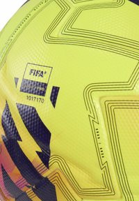 Keltainen ja musta FIFA Quality Pro -jalkapallo, jossa on teksturoitu pinta ja mustia geometrisia viivoja, merkitty kaudelle 2025/2026.