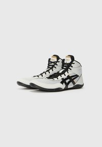 High-top athletic shoes in white, black, and gold. Features a textured upper, black laces, and a rubber sole with a sleek design.