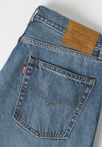 Πίσω τσέπη μπλε τζιν με κόκκινη ετικέτα Levi's και καφέ δερμάτινη ετικέτα Levi Strauss & Co. στην μέση.