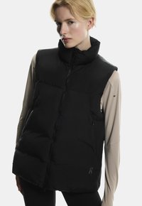Sort puffer vest med høj krave, lynlås lukning og sidelommer. Glat tekstur, letvægtsdesign og logo på nederste højre.
