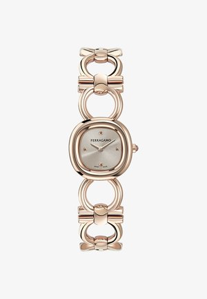 Ura Ferragamo v rožnato zlati barvi z okroglo srebrno številčnico, minimalističnim številčnico in povezavami na paščku v obliki povezane krožne oblike in pentlje.