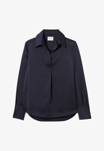 Blouse bleu marine à manches longues, en tissu lisse, présentant un col classique, une patte de boutonnage à l'avant et des poignets boutonnés. Détails de plis subtils.