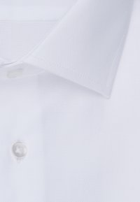 Primo piano del colletto di una camicia bianca e un bottone su tessuto liscio e strutturato.