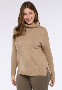 Beige svetr s rolákem s texturovaným diagonálním vzorem a akcenty z flitrů. Hladké manžety a lem, boční rozparky a měkký pletený materiál.