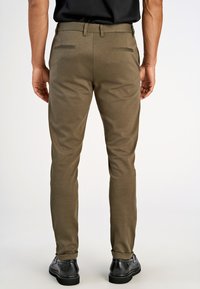 Herren Chino-Hosen in Olivgrün mit tailliertem Schnitt, zwei Gesäßtaschen und gekrempeltem Saum, aus einem weichen, dehnbarem Material gefertigt.
