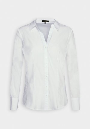 Chemisier pour femmes blanc à manches longues, boutonné, avec un col et des coutures ajustées, présenté à plat sur un fond uni.