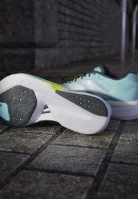 Lightweight athletic shoes featuring a mint green upper, black accents, and a textured white midsole with a distinct patterned black outsole.