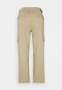Beige cargo-housut, joissa on suora lahje, valmistettu pehmeästä puuvillakankaasta, ja joissa on kaksi sivutaskua sekä napitettu takatasku.