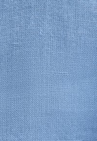 Gros plan d’un tissu bleu clair tissé serré montrant un petit motif carré uniforme et une surface texturée.