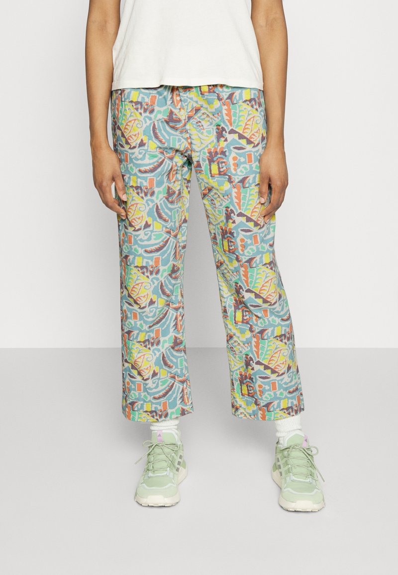 Colorful, patterned wide-leg pants in blue, green, orange, and red.  Features a relaxed fit and soft fabric, paired with light green sneakers.