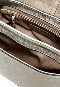 Grijze, gestructureerde leren handtassenv interior met een groot hoofdcompartiment en een kleinere met rits afgesloten zak met een zachte bruine voering.