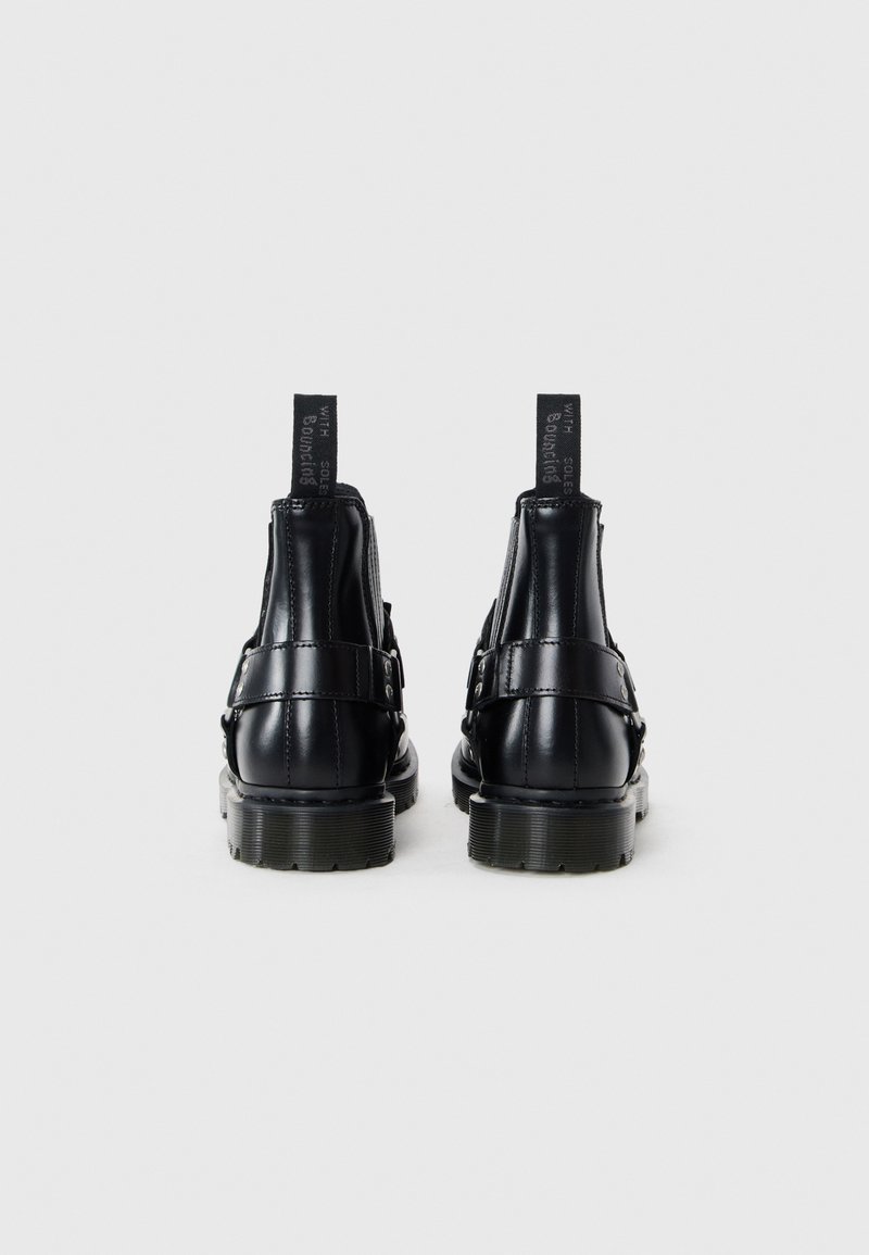 Bottines en cuir noir à finition lisse, dotées d'une semelle en caoutchouc épaisse, d'accents de boucle et de languettes à l'arrière pour un enfilage facile.