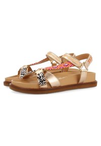 Guld sandaler med en flettet rem, flerfarvet perledesign og flad sål. Har justerbare ankelremme og et struktureret mønster.