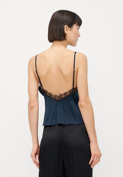 Jūras spēku zila zīda kamzolis ar mežģīņu apdari aizmugurējās apakšmalas un kakla līnijas daļā. Iespējamas regulējamas siksnas un brīva piegriezuma dizains.