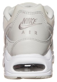 Nike Air sneaker in light grey leather with textured accents, padded collar, and transparent air cushioning at the heel.