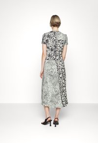 Czarna i biała midi sukienka w wzory z krótkimi rękawami, z kontrastowymi panelami i luźnym krojem.