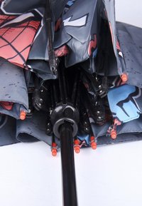 Ombrello pieghevole nero con una copertura a motivo, caratterizzato da tonalità di grigio, dettagli rossi e un manico nero, chiuso e riposto in modo compatto.