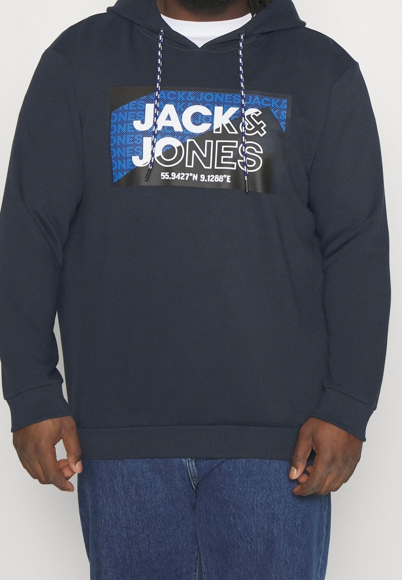 Mörkblå hoodie med ett framsidegrafik som visar "JACK & JONES" och koordinater. Inkluderar dragsnören med en texturerad yta och mjukt tyg.
