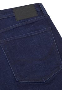 Jeans de mezclilla azul oscuro con una etiqueta de cuero negra en la cinturilla, que presentan un diseño de bolsillo trasero curvado y detalles de costura sutiles.