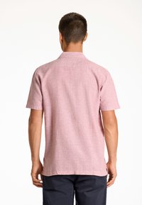 Korte mouwen, kraagoverhemd van lichtroze, gestructureerde stof. Het heeft een rugplooi, zijsplitten en een casual pasvorm.