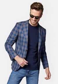 Niebieska marynarka w kratę z brązowymi akcentami, charakteryzująca się dopasowanym krojem, klapami, dwoma guzikami oraz miękką strukturą, noszona na granatowej koszulce.