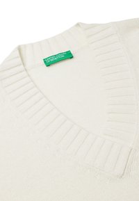 V-Ausschnitt Pullover in Cremefarbe, aus weichem Strickmaterial gefertigt. Mit gerippter Textur am Kragen und Saum. Grünes Markenetikett sichtbar.